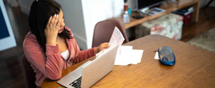 Woman at computer with hands on face, frustrated.