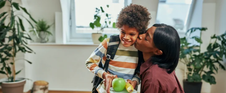 Mother giving son a kid on the cheek as he leaves for school.